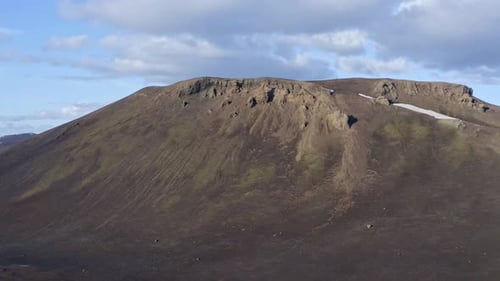Aerial drone view with an orbiting left movement, facing a green and rhyolite mountain in Landmannal