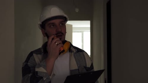 An Engineer Walks Along a Dark Corridor at a Construction Site