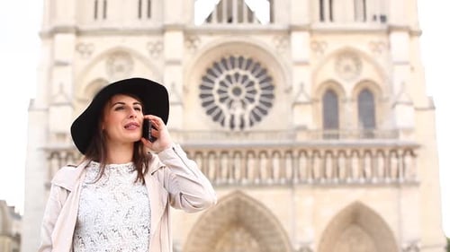 Woman in Paris using her mobile phone with Notre Dame cathedral on background