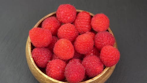 Ripe raspberries close up rotate in a wooden bowl. Juicy fresh raspberry berry is healthy