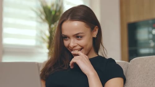 Woman Laughing While Using Laptop on Sofa