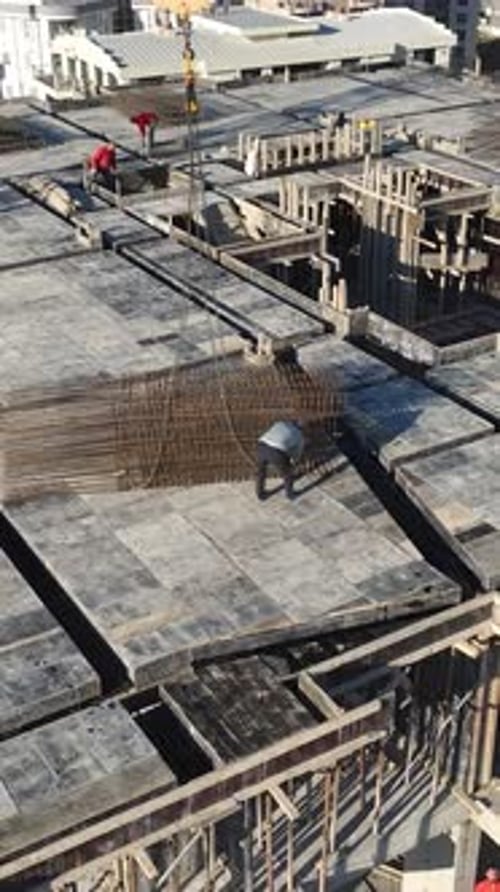 Vertical Video Tower Crane Above Concrete Building Under Construction with Urban Development Around