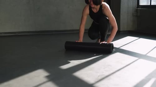Woman Unrolls Yoga Mat in Bright Room
