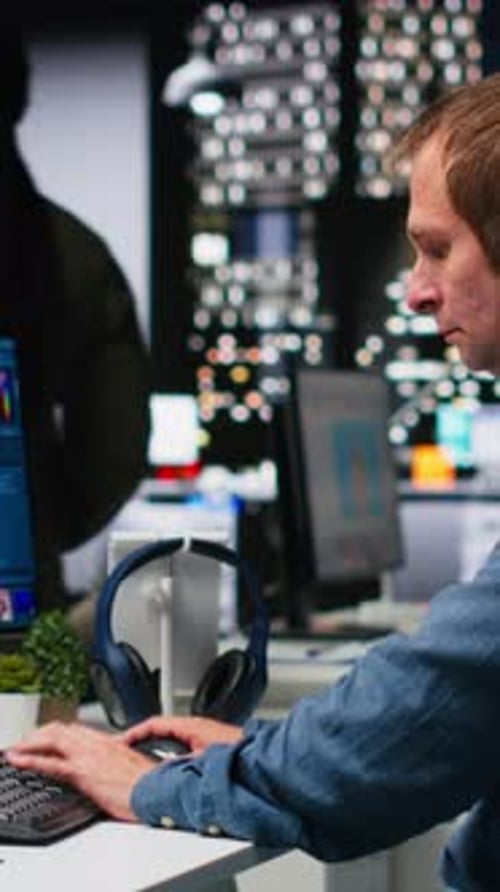 Man Works at Computer Wearing Headphones at Night