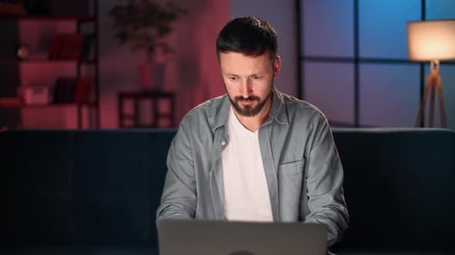 Man Typing on Laptop at Home at Night