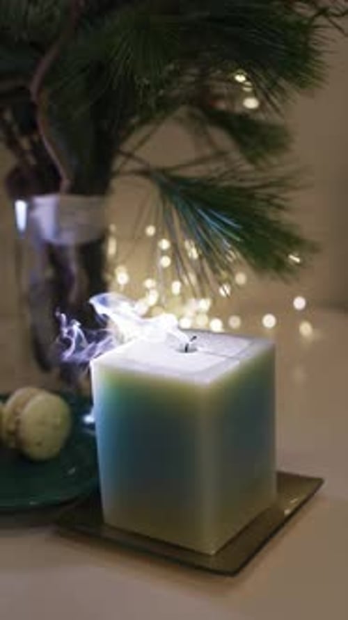 Burning candle close-up. Decorated christmas tree on background. Winter holidays concept. Celebratin