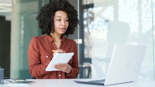 Young Woman Taking Notes During Video Call