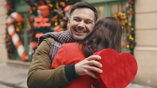 Loving Couple Embracing with Gift Outdoors