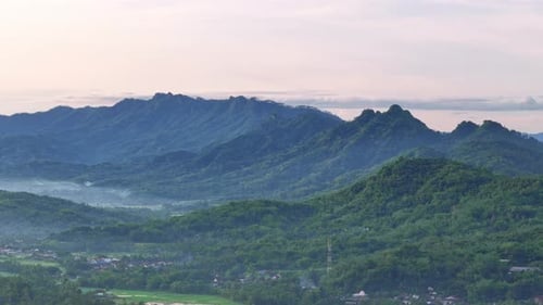 Aerial view of beautiful scenery of green rain forest with hills in slightly foggy morning.