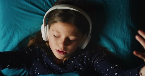 Smiling Girl Lying on Bed with Headphones