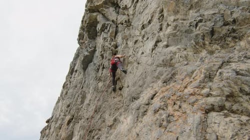 Young Woman Climbing Up Steep Rock