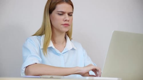 Young caucasian businesswoman using laptop computer while looking document on desk in living room.