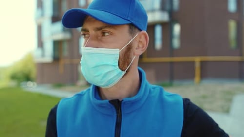 Portrait Delivery Man Holding Cardboard Box at Street Look at Camera Wear Protective Medical Face