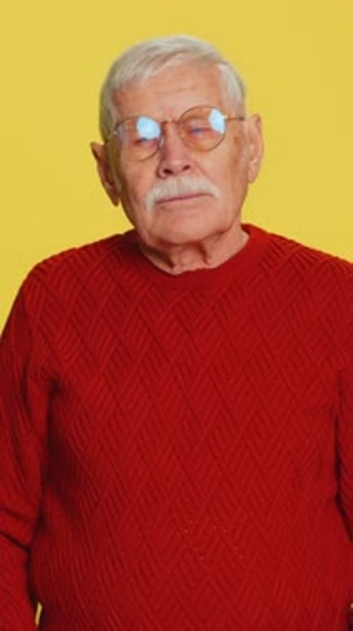 Senior Man Rubbing Eye on Yellow Background