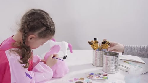 Little Girl Painting Paper Mache Figurines with Acrylic Paint for Her Homeschooling Art Project