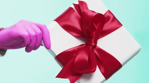 Hand in Pink Glove Holding a Gift