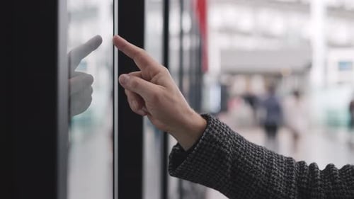 Closeup of a Hand Touching a Screen in a Public Space Represents the Concept of Modern Technology