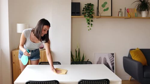 Young Woman Cleaning Table in Bright Apartment