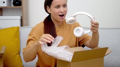 Woman Excitedly Unboxing New Headphones at Home
