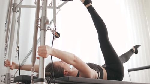 Woman Practices Pilates on Machine Indoors