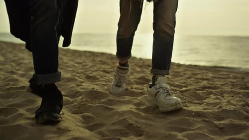 Unrecognizable couple walking on sand beach enjoying sunset sea vacation together