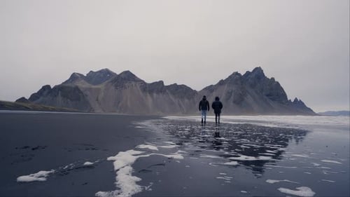 Couple Walking on Black Sand Beach with Mountains