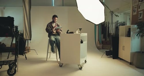 Man, photographer and check on tablet in studio with photoshoot results, editing and catalog