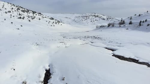 Aerial view of beautiful mountain valley covered in snow mountain peak at the distance winter day
