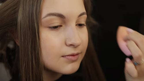Makeup Artist Applying Foundation to Young Woman's Face