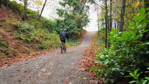 A man riding a bicycle uphill on a sloppy road - riding a bicycle steep uphill, hard-pushing pedals