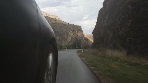 Car Driving on Road Through Mountain Canyon