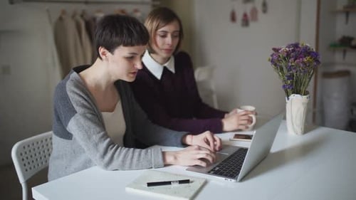 Two young women using laptop at table