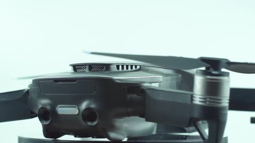 Close up shot of a Drone with camera lens and propellers, silver grey color, on a rotating 360 stand