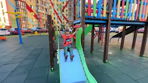 Caucasian toddler in bright t-shirt and pants playing on the playground.
