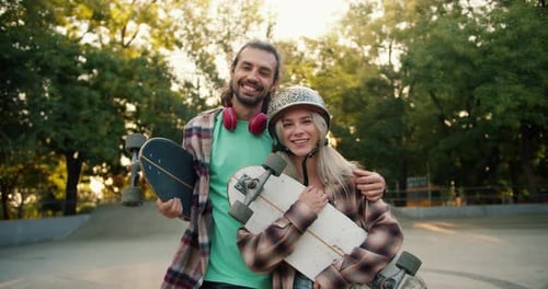 A Blonde Girl in a Leopard Print Helmet and a Plaid Shirt Stands with a Brunette Guy in a Green