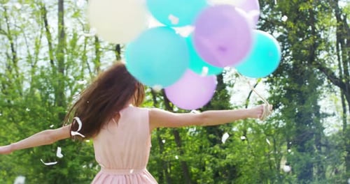 Joyful Woman Celebrates with Balloons and Confetti Outdoors
