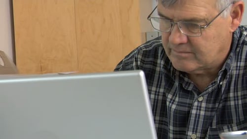 Man Working at Desk with Laptop, Plaid Shirt