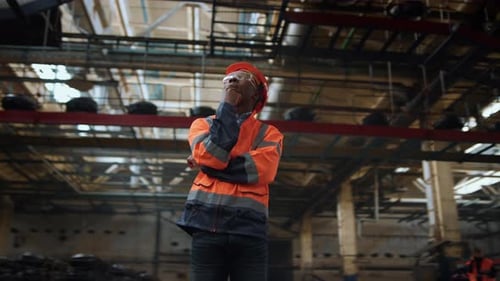 Industrial Supervisor Analyzing Work Wearing Safety Uniform at Modern Warehouse. Focused Serious