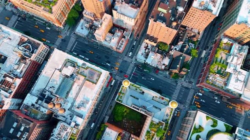 Flying over the streets and blocks of New York at daytime. Cars and yellow taxi ride by the roads.