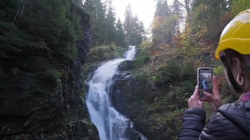 Woman Filming Waterfall with Phone in Nature