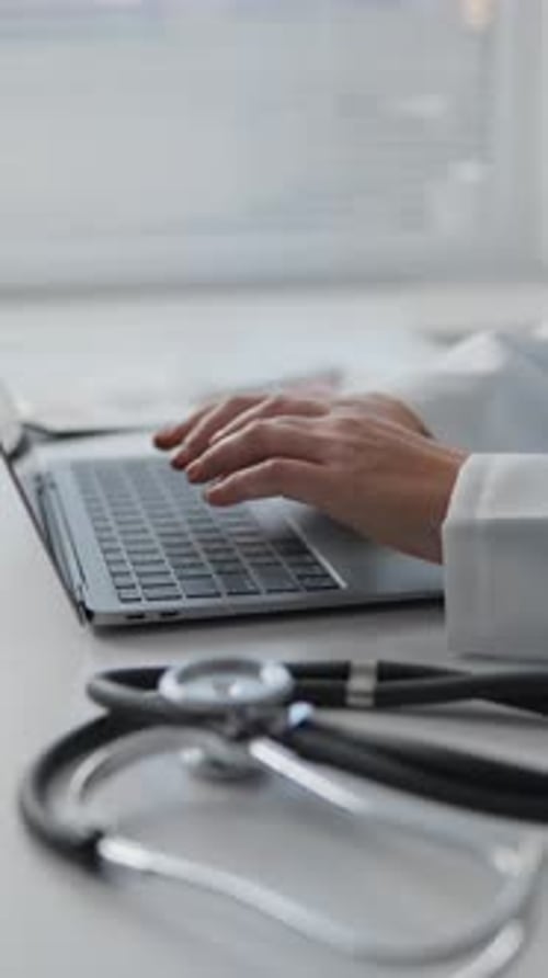 Doctor Typing on Laptop with Stethoscope Beside