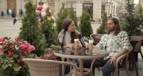 Young Couple Man and Woman Sitting at Table Trendy Cafe on a Summer Day