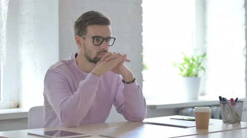 Young Man Thinking While Sitting in Office
