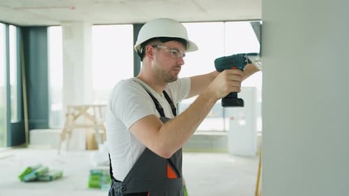 Construction Worker Drilling Wall for Drywall Installation