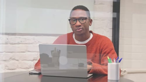 Young Adult Works at Laptop in Office Smiling