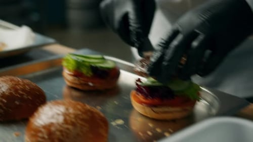 Gloved Cook Assembling Hamburgers in Kitchen