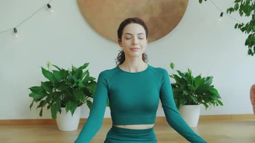Meditative Woman Practicing Yoga in a Serene Indoor Space Surrounded By Plants During Daylight Hours