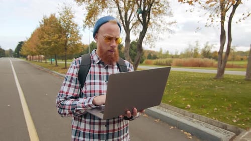 Man Uses Laptop Outdoors in Autumn Park Setting