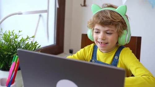 Child Wearing Headphones Uses Laptop at Home