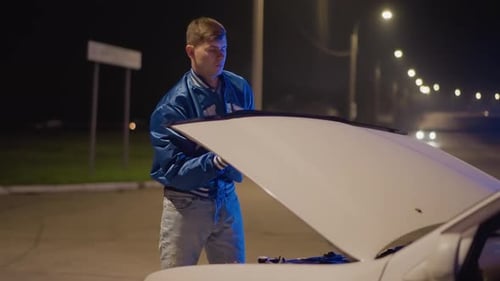 Man Inspects Car Hood Carefully Male Parks Vehicle and Examines Engine Bay Attentively Nighttime